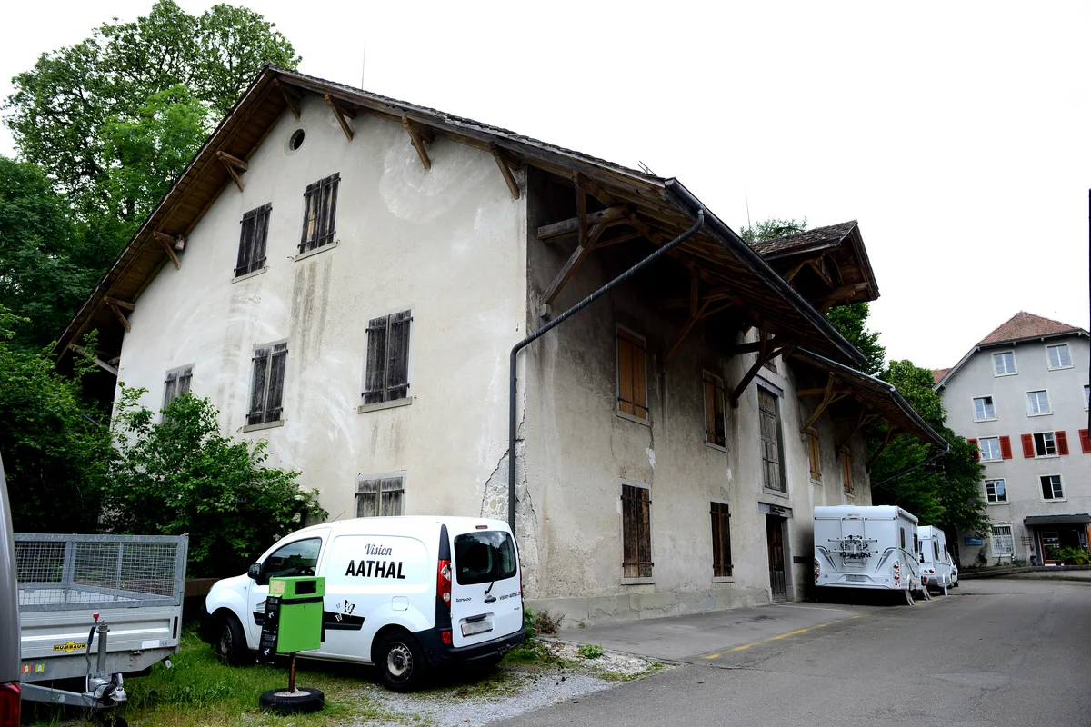 Ein altes Haus mit Wohnwagen und Autos.